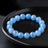 Bracelet of round pale blue aquamarine beads resting on a dark plate