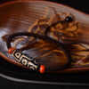 Nine-eye dzi bead on a braided brown cord bracelet with red agate beads