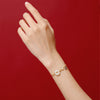 Red string bracelet with a white jade peace buckle charm on a wrist