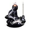 Black glazed ceramic backflow burner with a lit cone on top and smoke flowing down over curved tiers