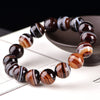 Bracelet of round brown agate beads with white and tan bands on a white surface