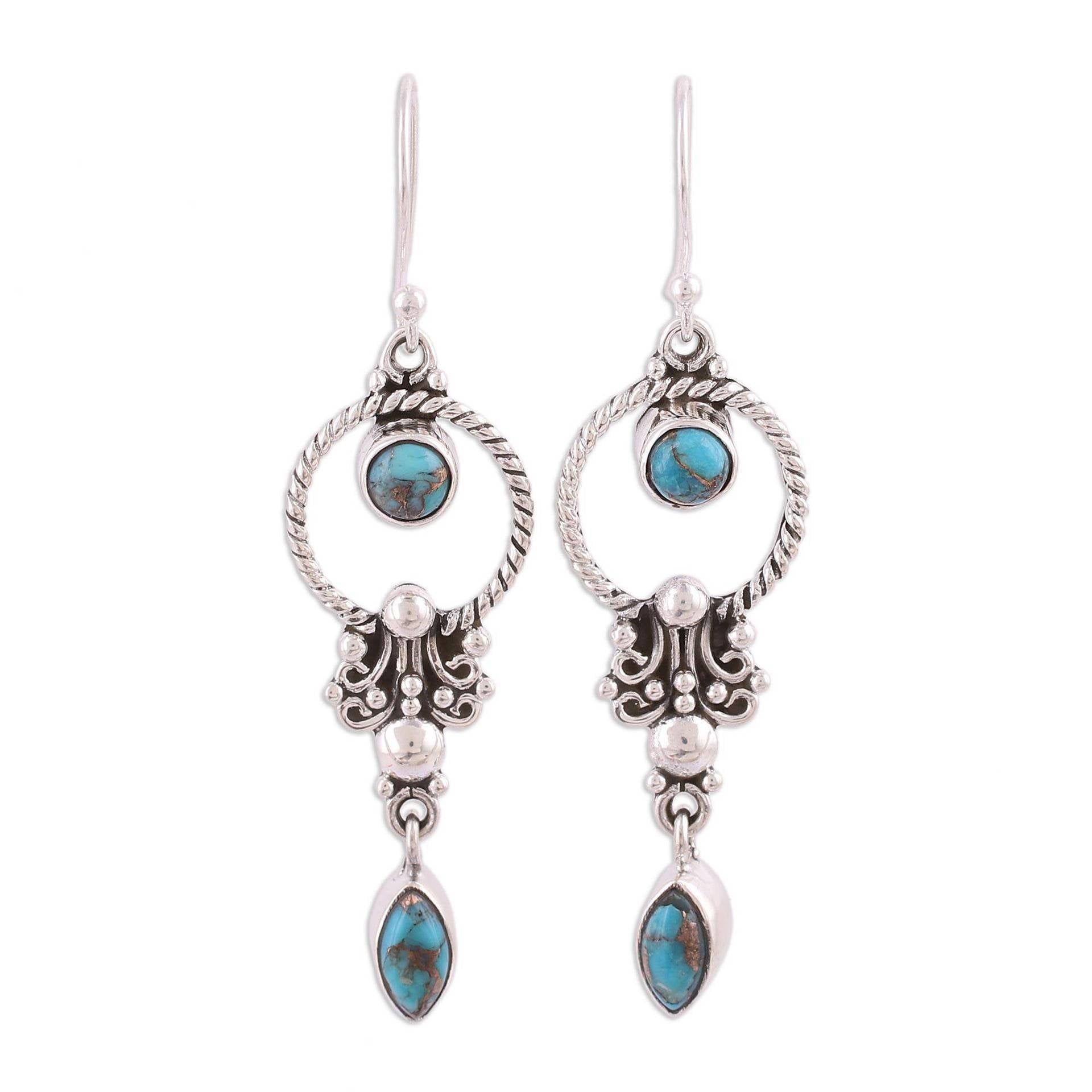 Pair of vintage silver tone copper drop earrings with faux blue stones hanging from a branch