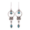Pair of vintage style silver tone dangle earrings with synthetic turquoise stones hanging from a branch