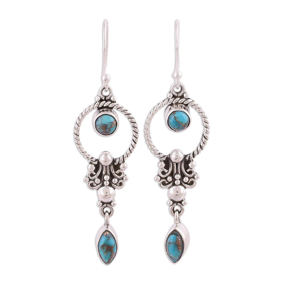 Pair of vintage style silver tone dangle earrings with synthetic turquoise stones hanging from a branch
