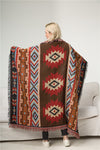 Close up of a geometric patterned cotton throw blanket with red and brown colors and fringe edges