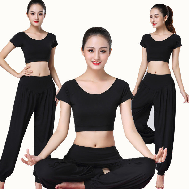 Woman wearing a solid color short sleeve top and loose harem pants sitting in a meditation pose