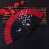 Black silk folding fan with red trim, white rabbits and pink flowers on display stand