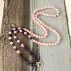 Pink and purple beaded bracelet with silver lotus charm on wood