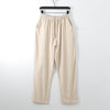 Beige men's loose cotton pants hanging on a hanger