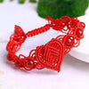 Close up of a red woven bracelet with crystal beads and a heart shaped knot