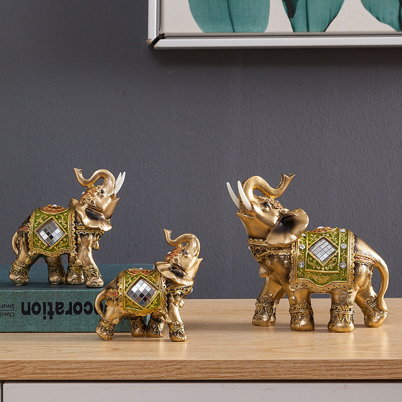Gold and green resin elephant statue with raised trunk on a wooden surface