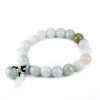 Close up of a natural jade beaded bracelet with a carved pendant on a wooden surface