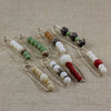Collection of beaded safety pin brooches with bodhi seeds and colored beads on linen fabric