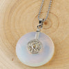 A white opal crystal pendant with a silver lotus charm on a wooden surface