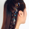 A side view of a woman wearing silver hair rings with dangling charms in her braided hair.