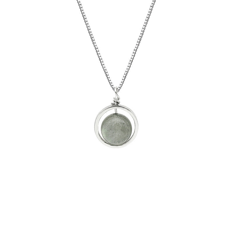 Woman wearing a silver necklace with a round moonstone pendant