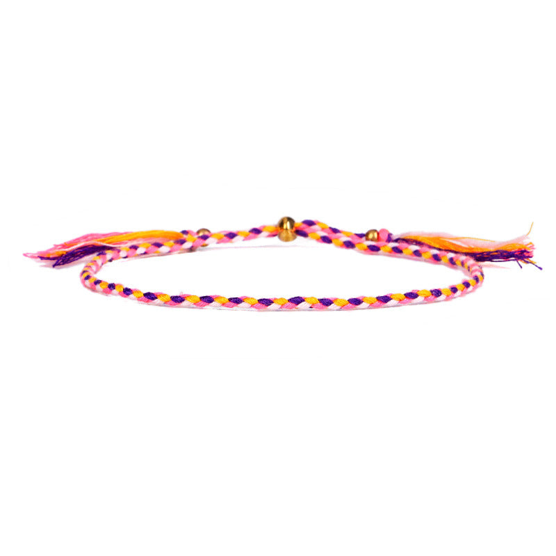 A multicolored braided cotton rope bracelet with gold-tone beads and tassels on a white background