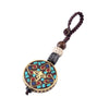 A round metal key chain with colorful enamel inlay and a braided cord held next to a car key fob.