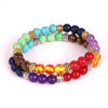 Multi-colored chakra bead bracelet with gold tone spacers on white background