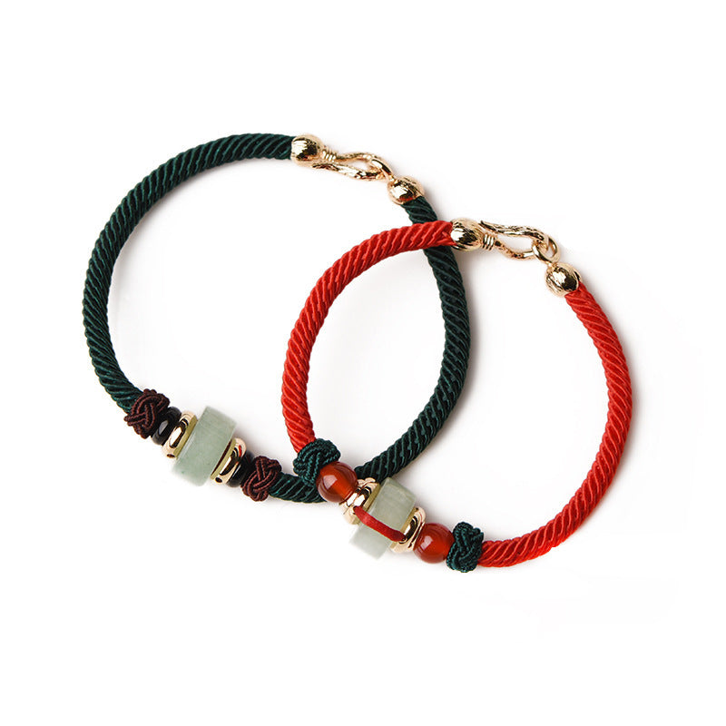 Two braided cord bracelets, one red and one green, each with a light green stone bead and gold clasp on a white background