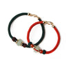 Two braided cord bracelets, one red and one green, each with a light green stone bead and gold clasp on a white background