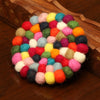 Round multicolor wool felt ball cushion on wood surface