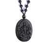 Close-up of a carved black obsidian pendant shaped like an elephant deity on a beaded necklace.