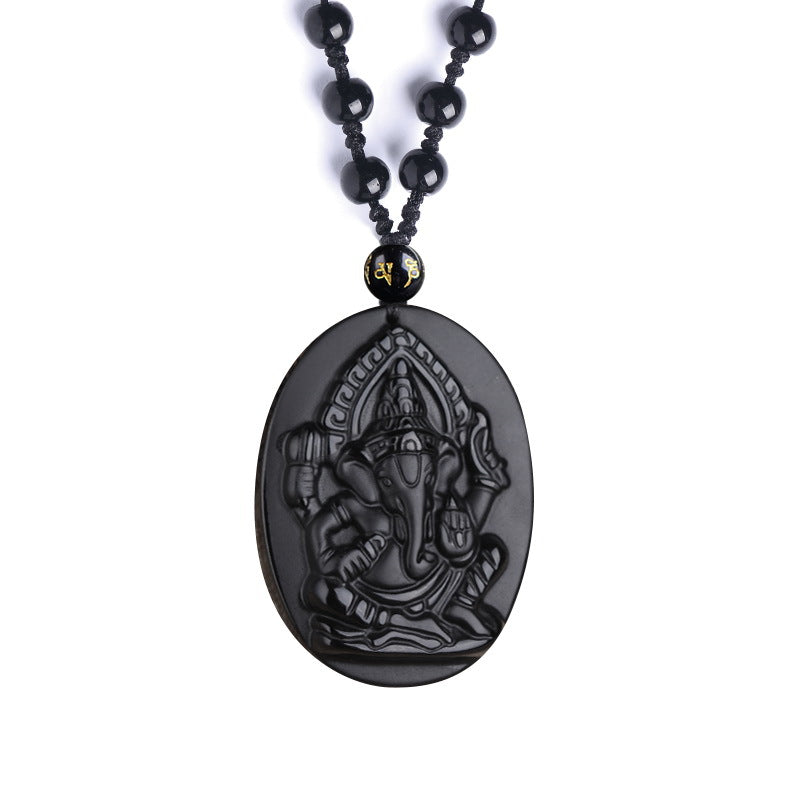 Close-up of a carved black obsidian pendant shaped like an elephant deity on a beaded necklace.