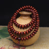 Reddish brown African blood sandalwood mala bracelet wrapped around a clay pot