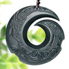 Close up view of dark green carved jade pendant with spiral designs