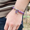 Wrist shot of a purple gemstone bracelet with a silver tree charm