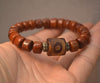 Close up of a brown ox bone bracelet with a large Dzi bead on a hand
