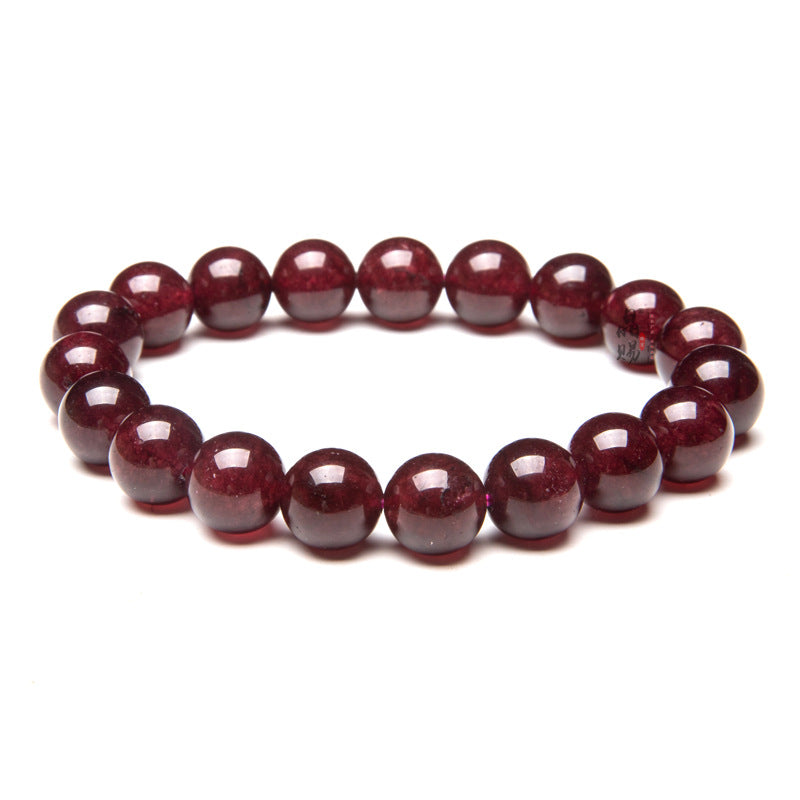 Deep red natural garnet bead bracelet on a black reflective surface
