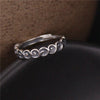 Close up view of a silver ring with a spiral cloud pattern on a dark surface