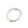 Clear quartz beaded bracelet with a gold dragon charm resting on a white dish