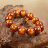 Close-up of a golden brown resin bracelet with wood grain texture resting on a piece of driftwood