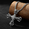 Close-up of a silver cross-shaped pendant with a double dorje design resting on wood