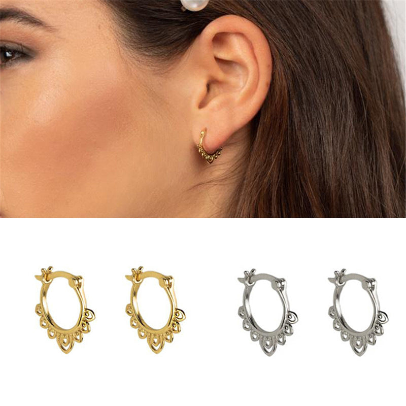 Close up of a woman wearing small gold hoop earrings with a lotus pattern