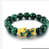 Close up of a green beaded bracelet with a gold and blue Pixiu charm