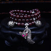 Multi-layered garnet bracelet with a crystal fox pendant on a black stand