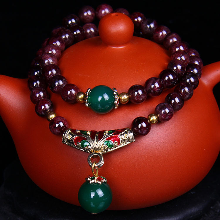 Double-wrap natural garnet beaded bracelet with gold-tone Pixiu charm on a teapot