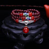 Deep red natural garnet wrap bracelet with red agate beads and a silver-tone pendant resting on a teapot