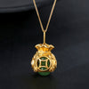 Gold tone money bag pendant necklace with green jade bead on dark background