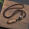 Long brown cord necklace with an oval agate pendant carved with white script characters