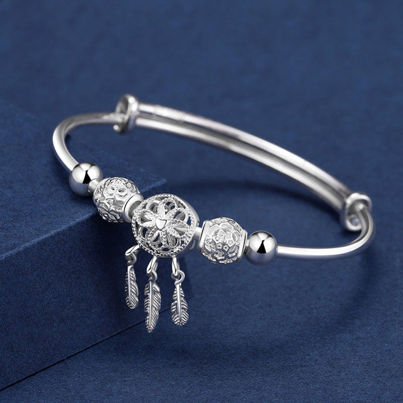 Close up of a silver plated white copper open bangle with a dream catcher charm