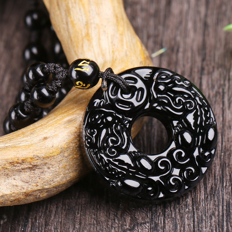 Close up view of a black obsidian pendant carved with two Pixiu designs