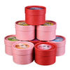 Stack of round pink and red boxes containing scented incense cones with one cone displayed on a holder.