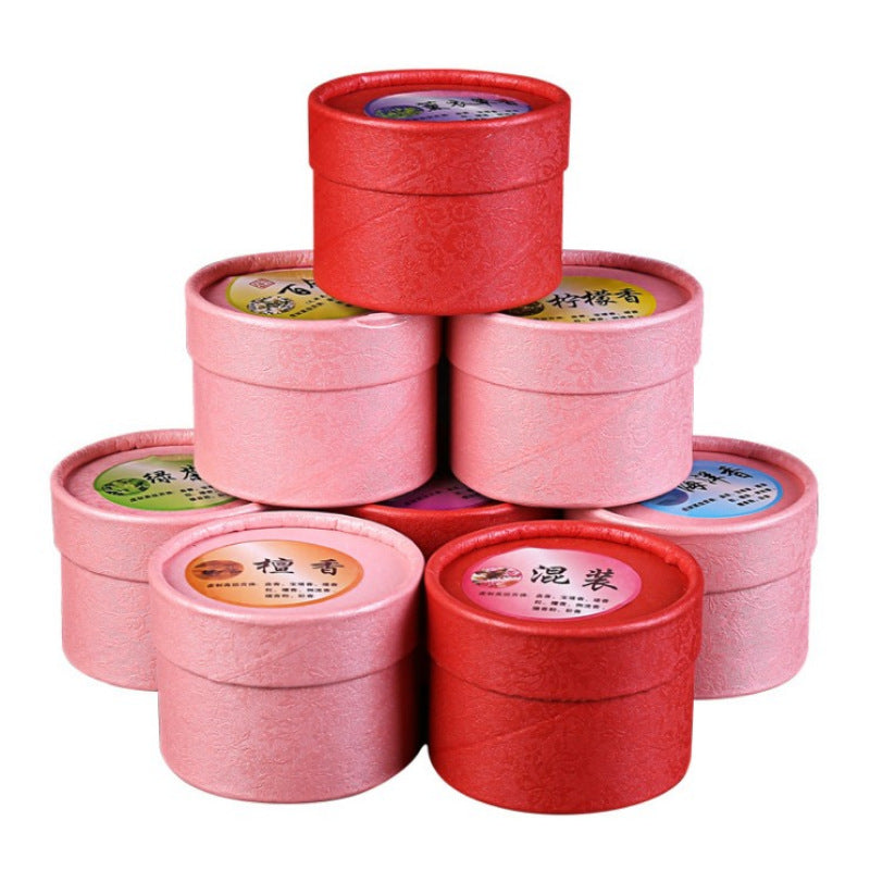 Stack of round pink and red boxes containing scented incense cones with one cone displayed on a holder.