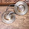 Pair of engraved bronze tingsha bells resting on a wooden surface