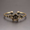 Close up of an antique brass open cuff bracelet with a flower design